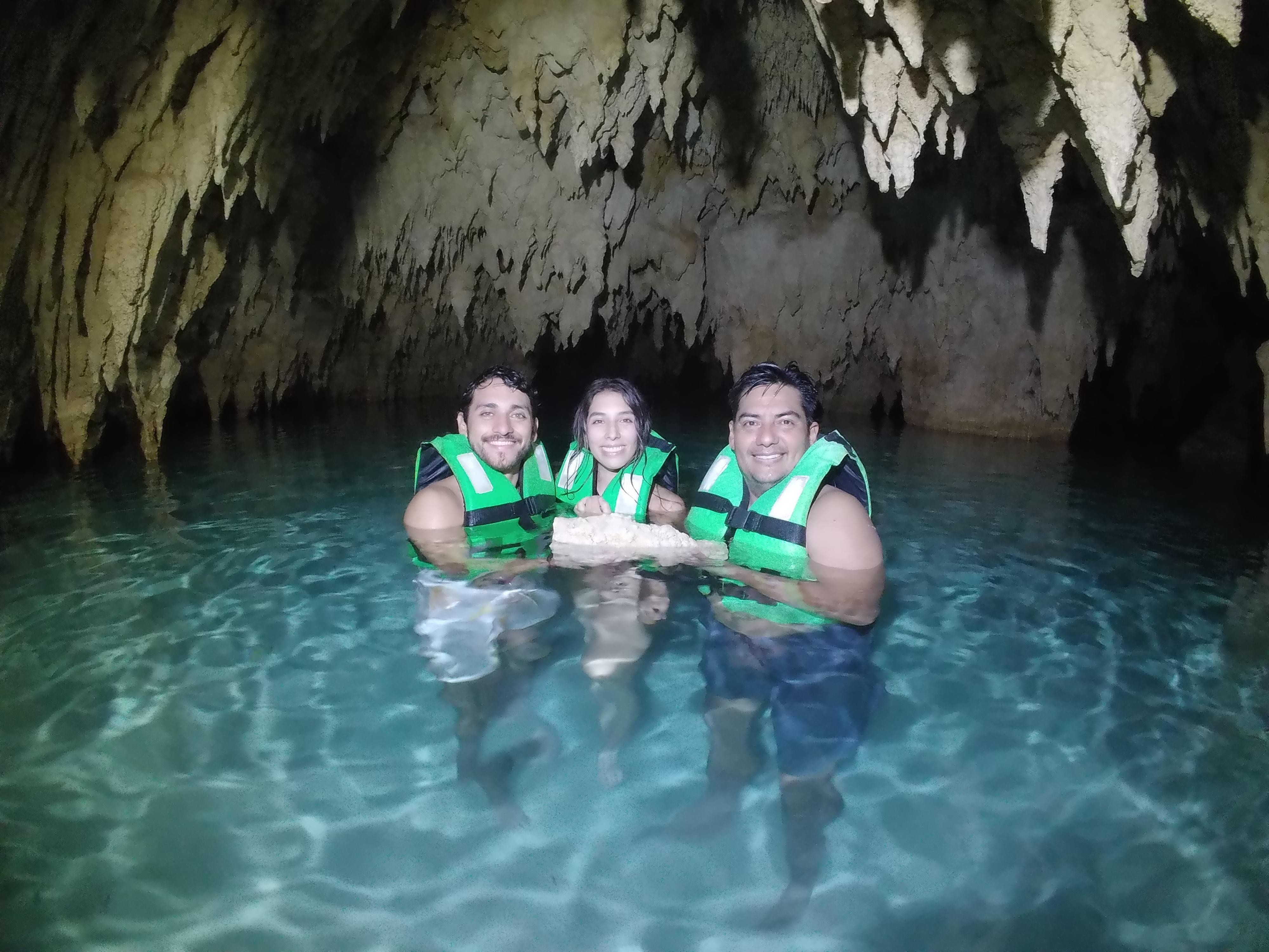 Three guests in life jackets inside a cave pool