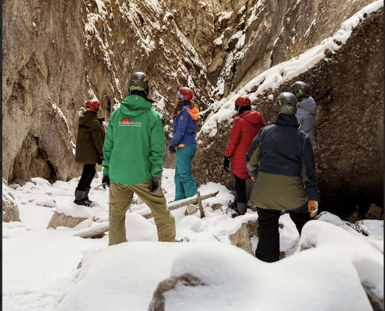 A guided group in helmets walking into snowy Pleckaitis Canyon in the Maligne Valley