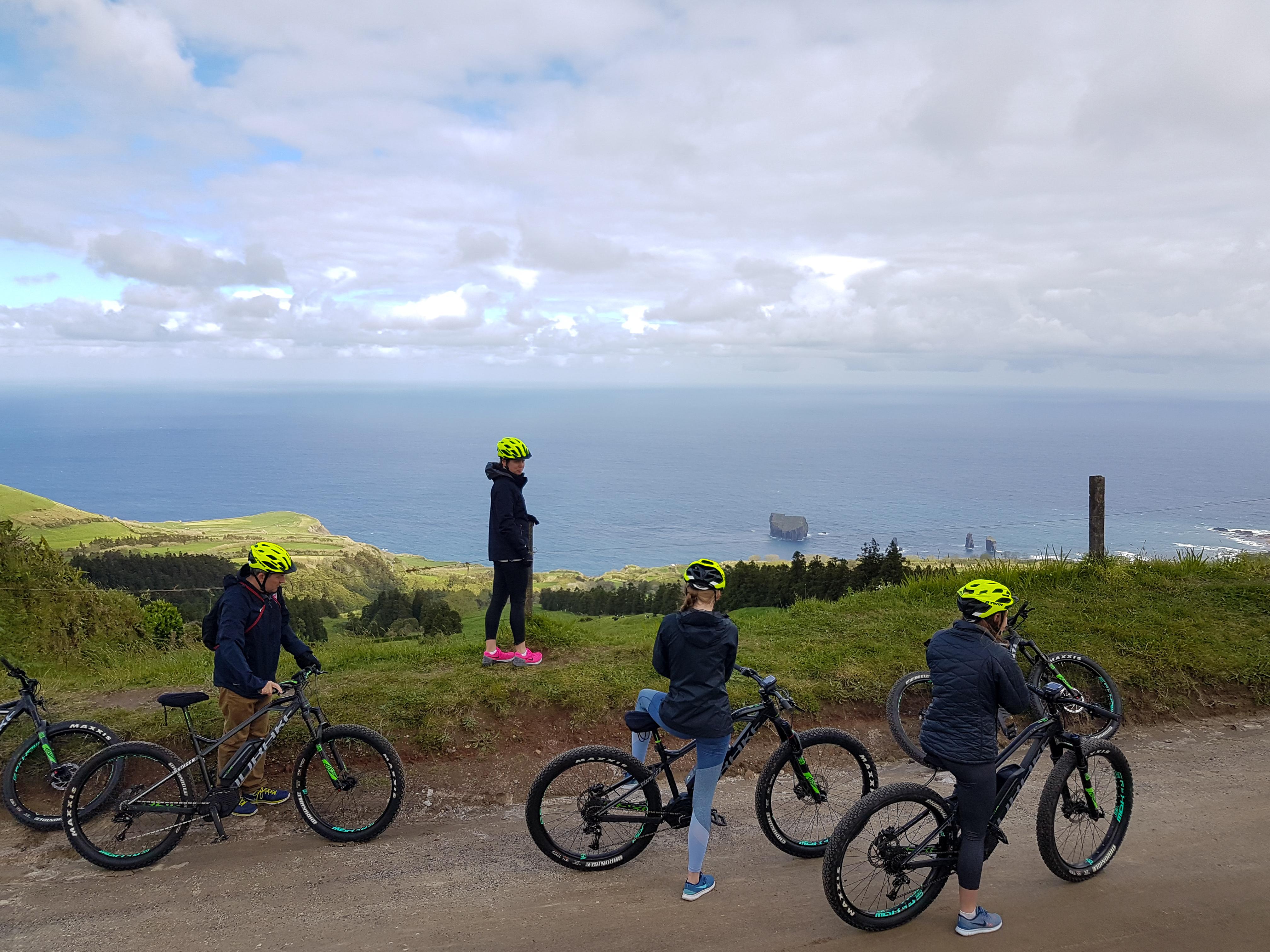 Cyclists resting with e-bikes at a high São Miguel viewpoint