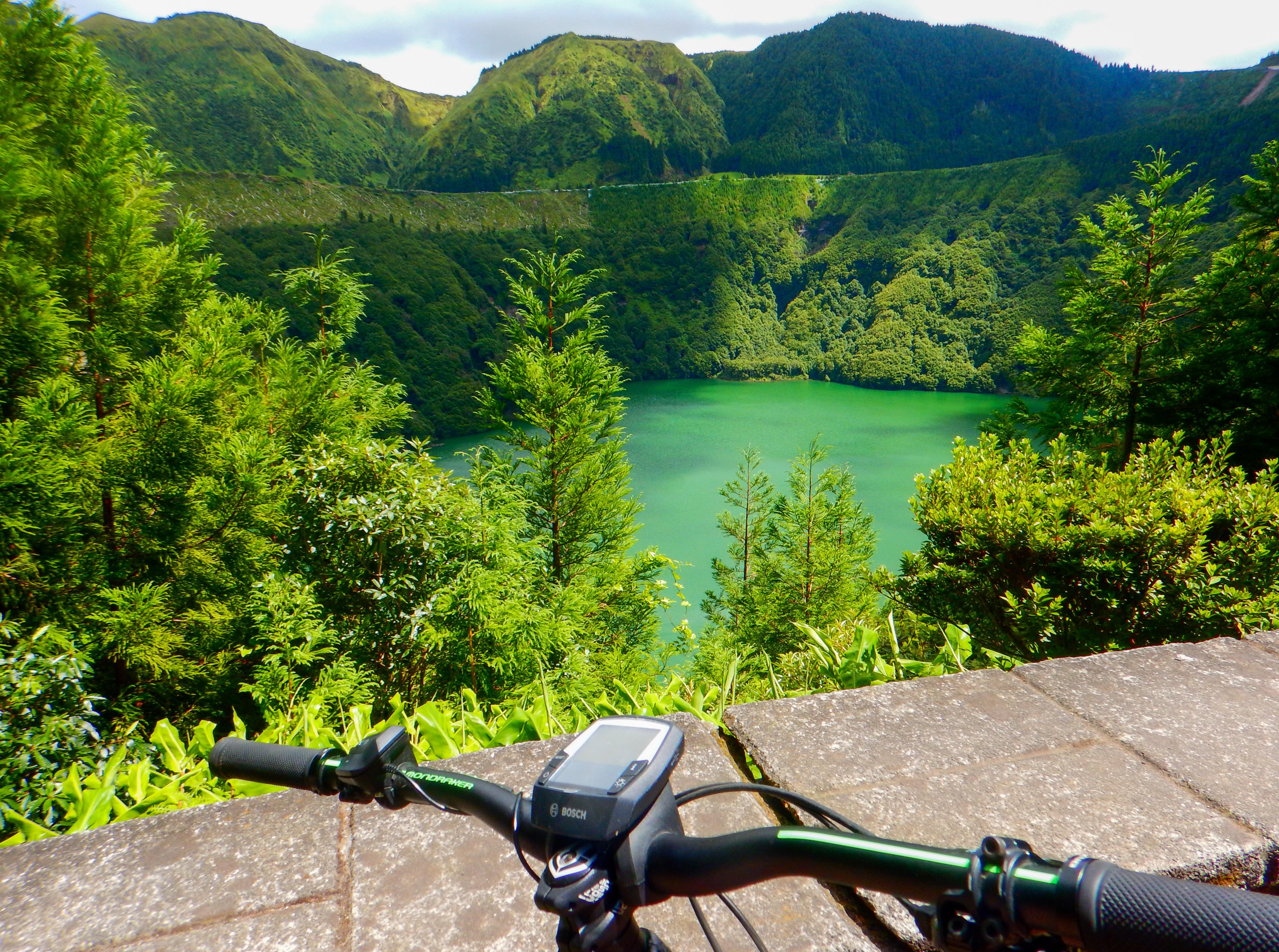 E-bike handlebars overlooking a steep green volcanic slope
