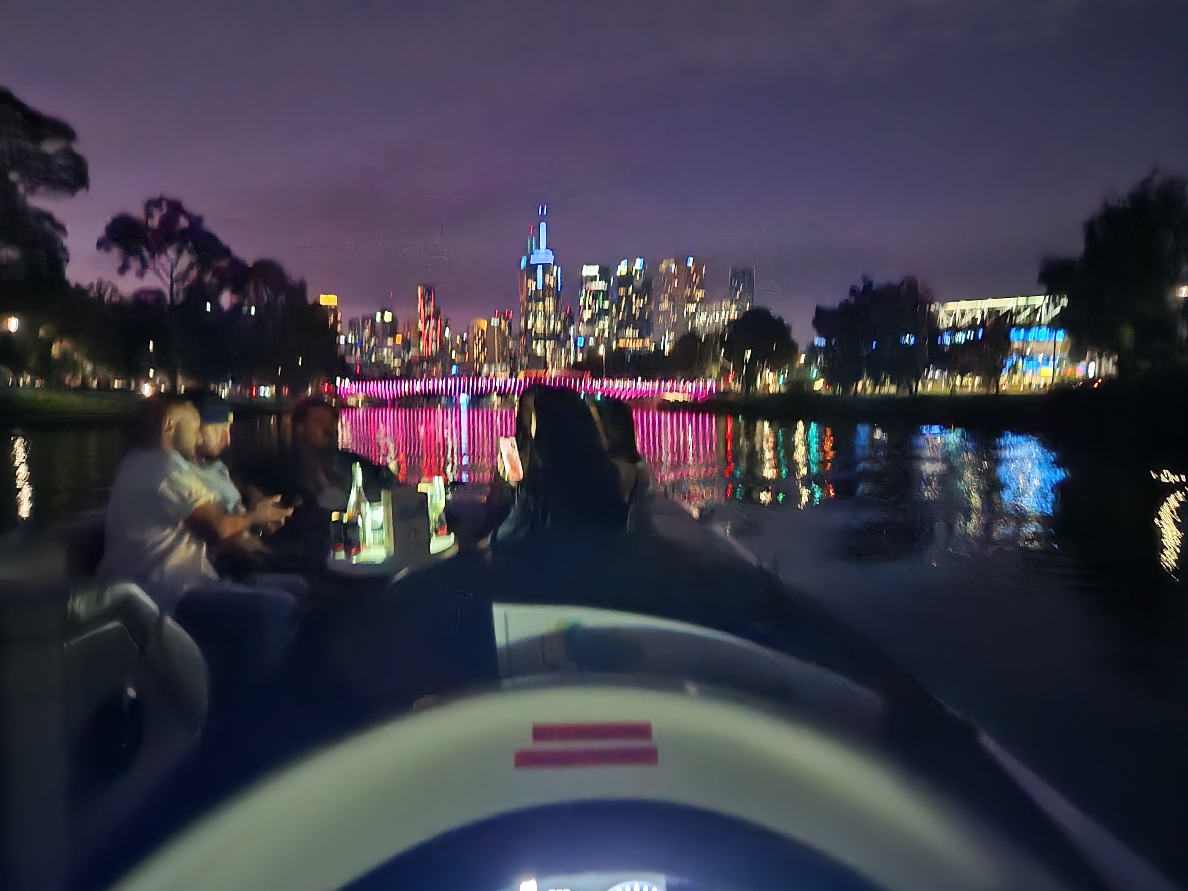 Melbourne's skyline lights on the Yarra at night, seen from a boat's helm