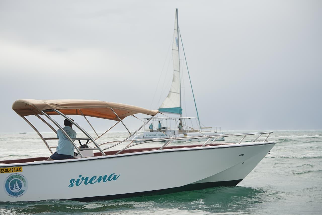 SirenaMoris speedboat with a shade canopy, with a sailing catamaran behind it