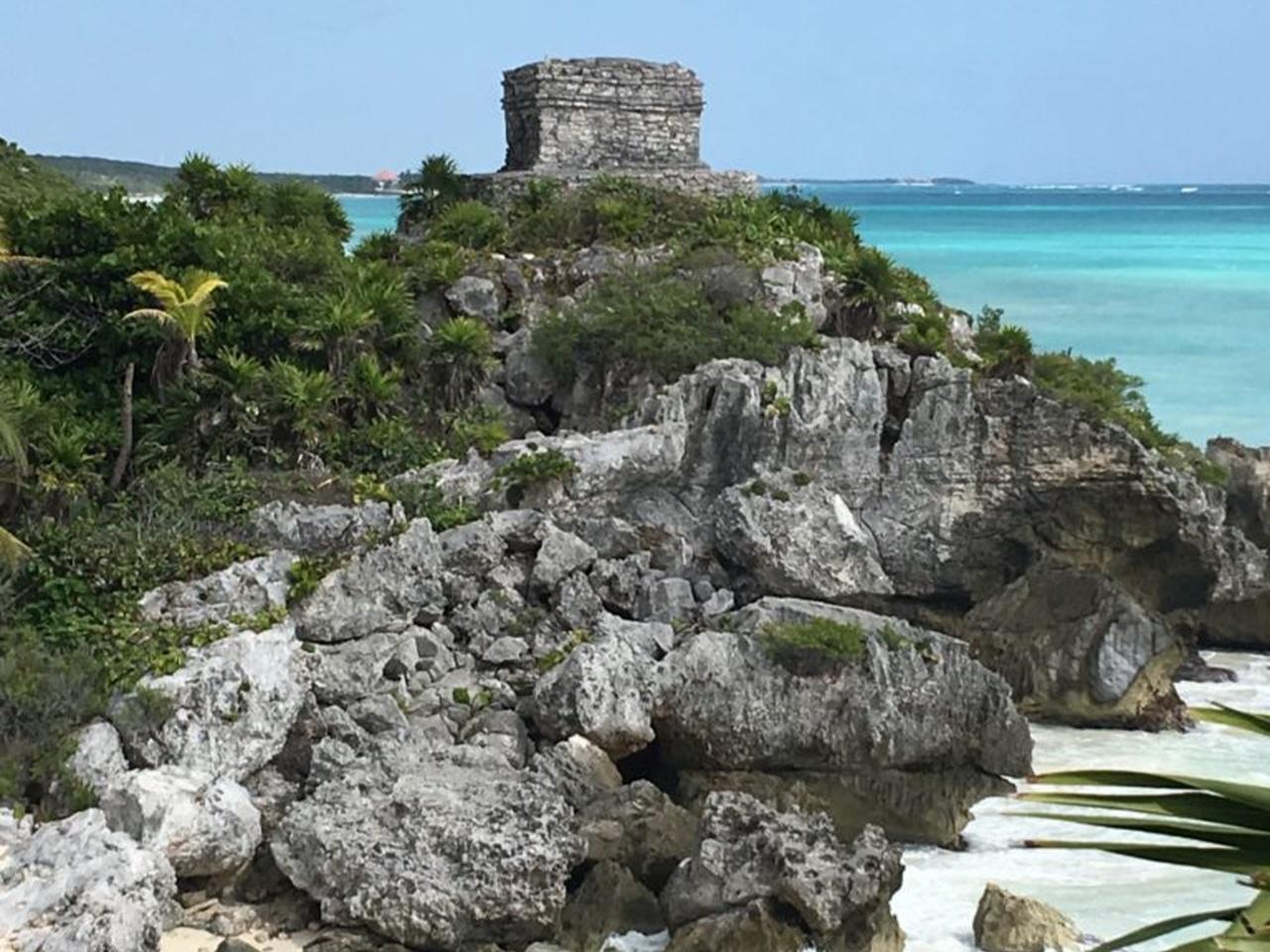 Stone Tulum ruin above a rocky coast and blue sea