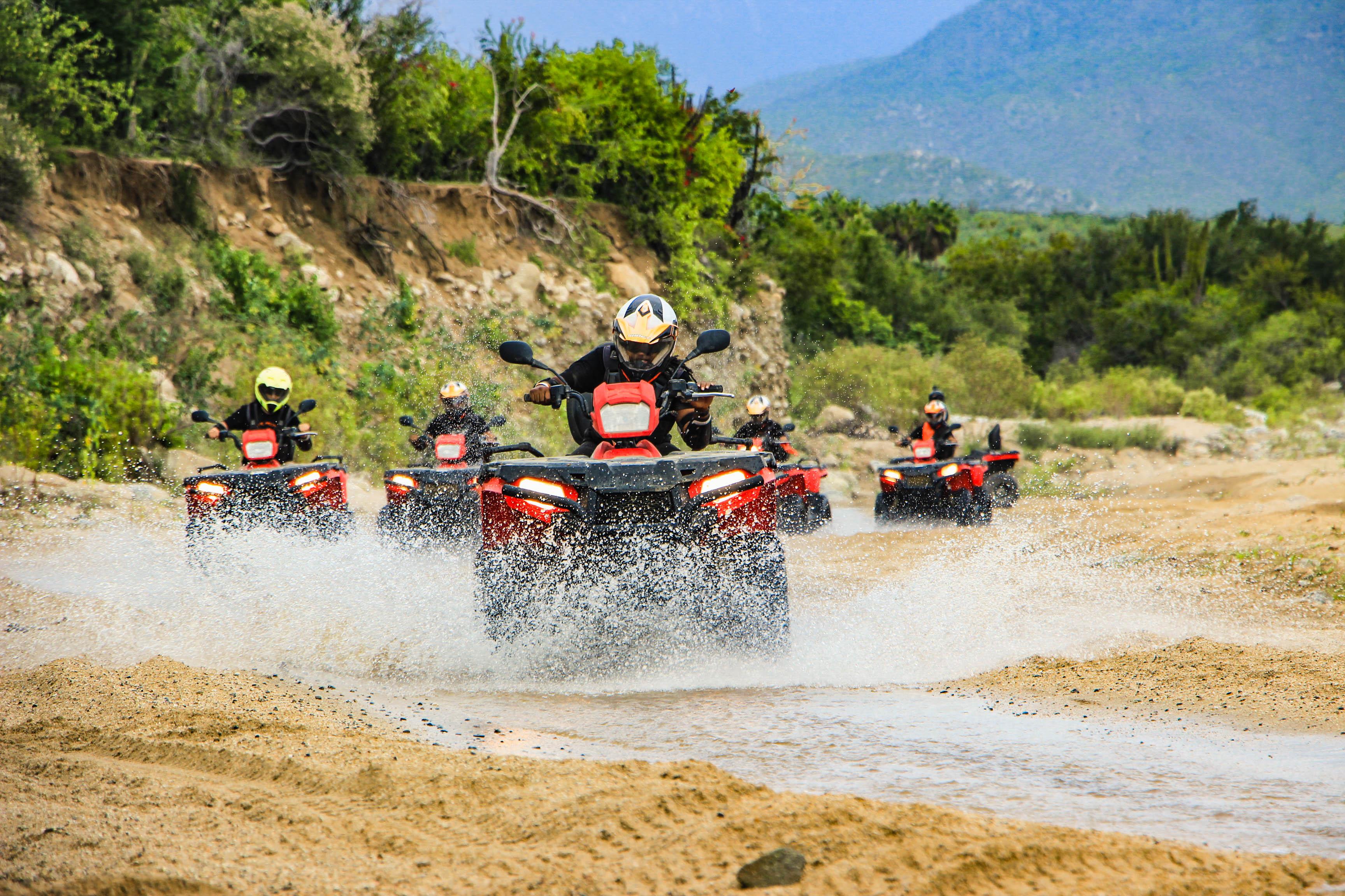 ATV riders crossing shallow water on the Cabo combo tour