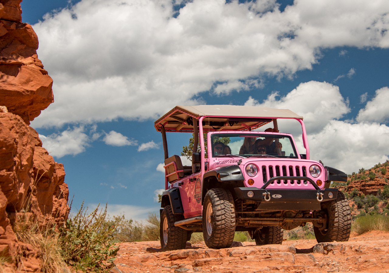 Sedona jeep tour — Pink Jeep Wrangler on Mogollon Rim with red-rock canyon panorama