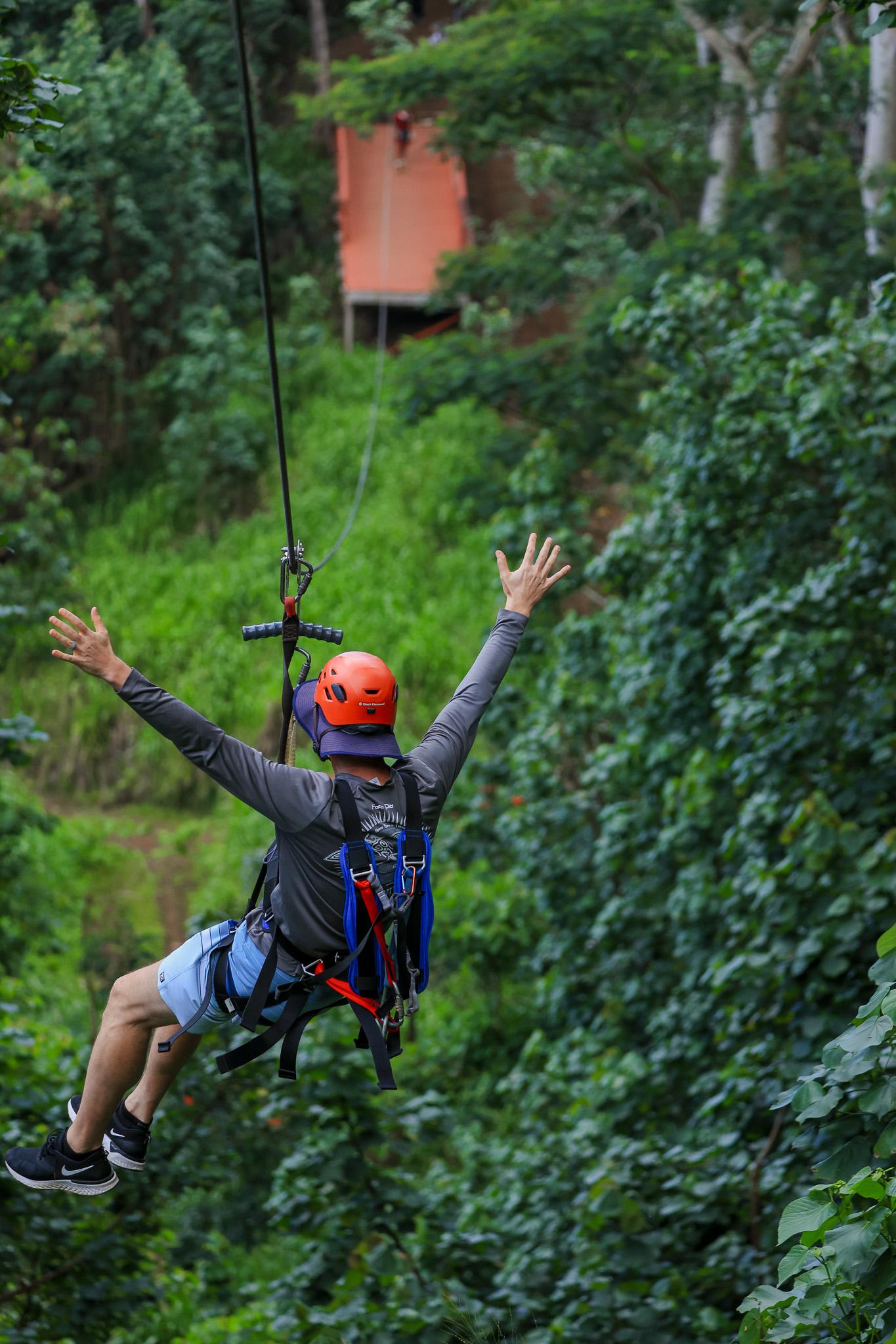 A helmeted rider gliding through dense green vegetation on the Koloa course