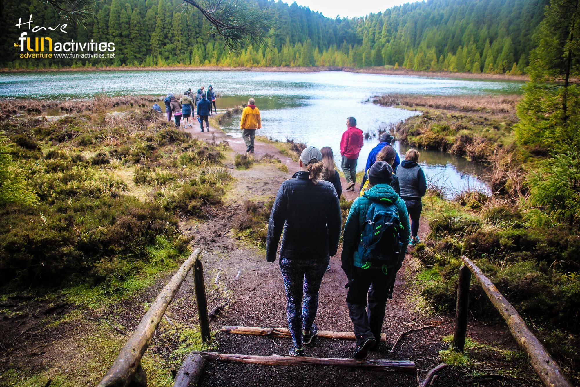 A guided group walking down wooden steps toward a reed-fringed lake