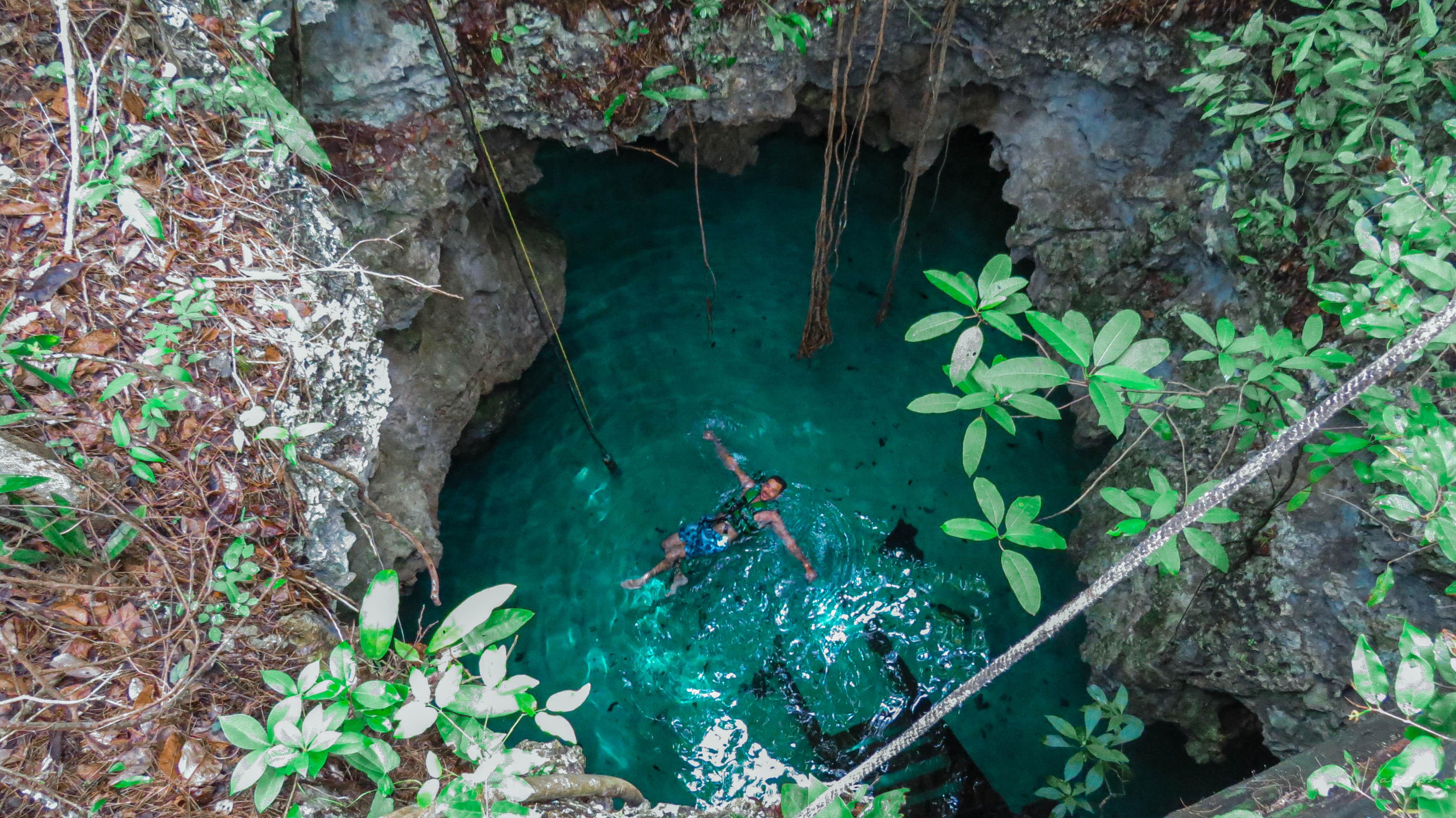 Swimmer floating in a small turquoise limestone pool