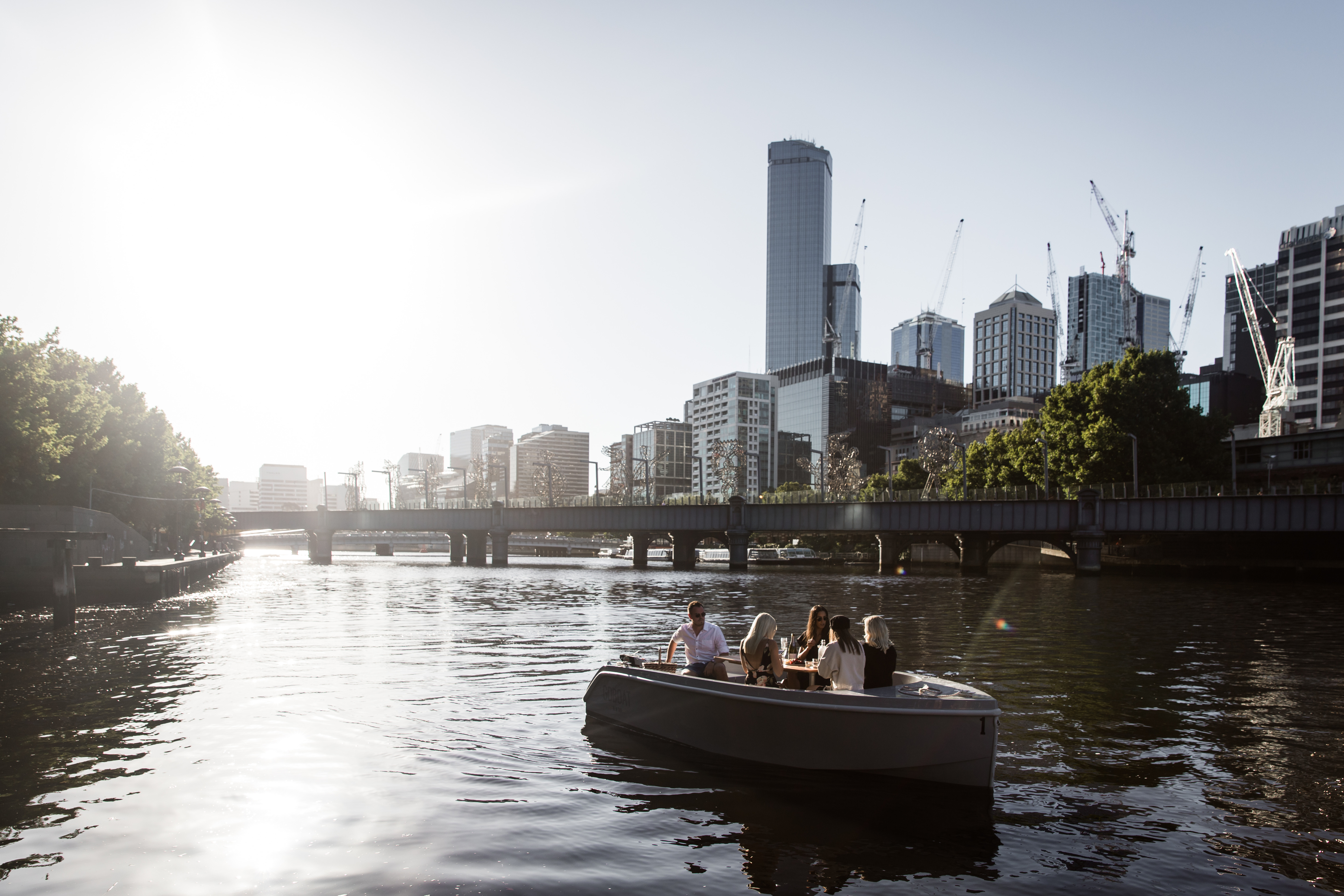 A GoBoat electric picnic boat on the Yarra with the city towers behind