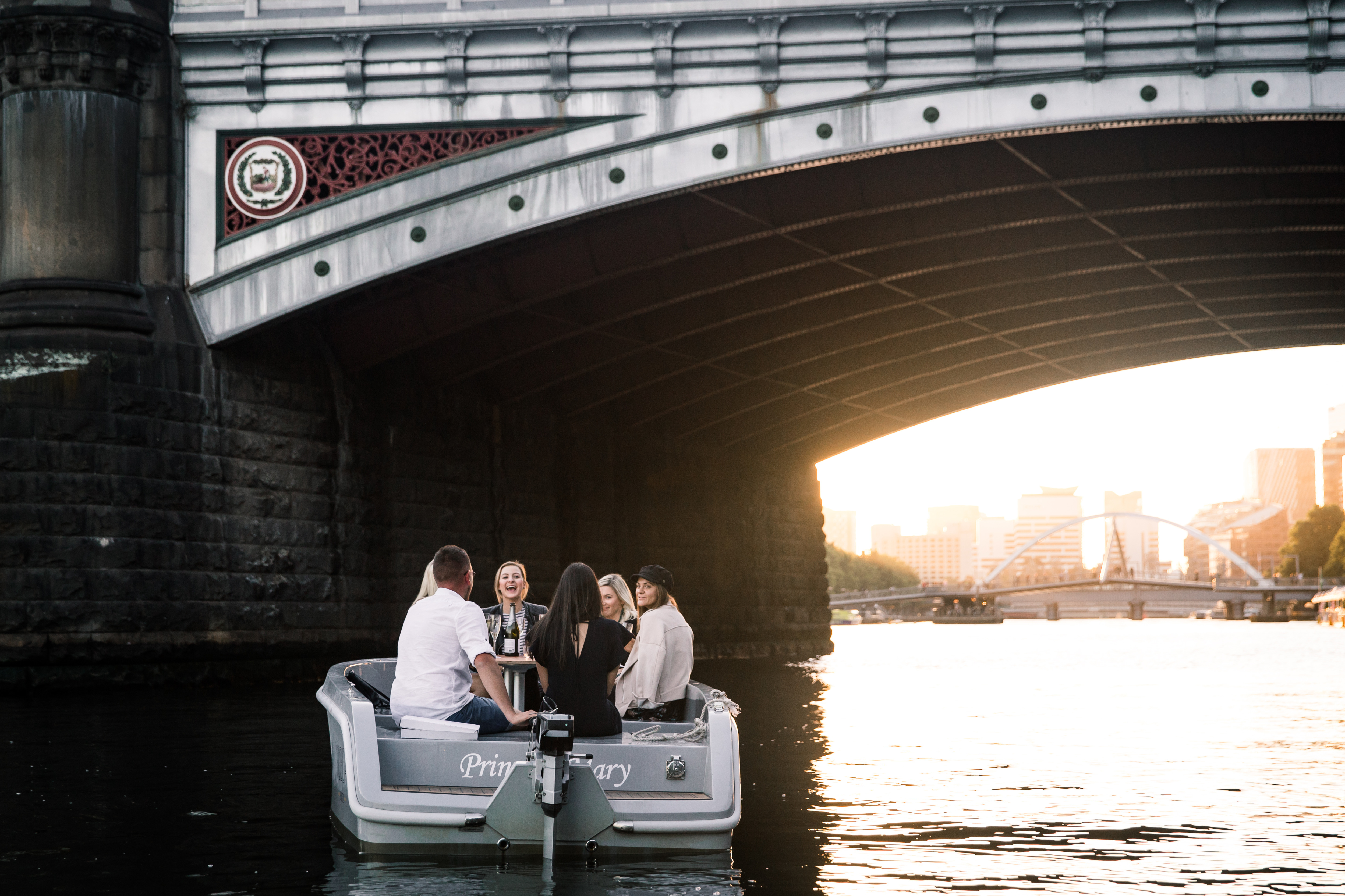 A GoBoat in the shade of a city bridge on the Yarra at sunset