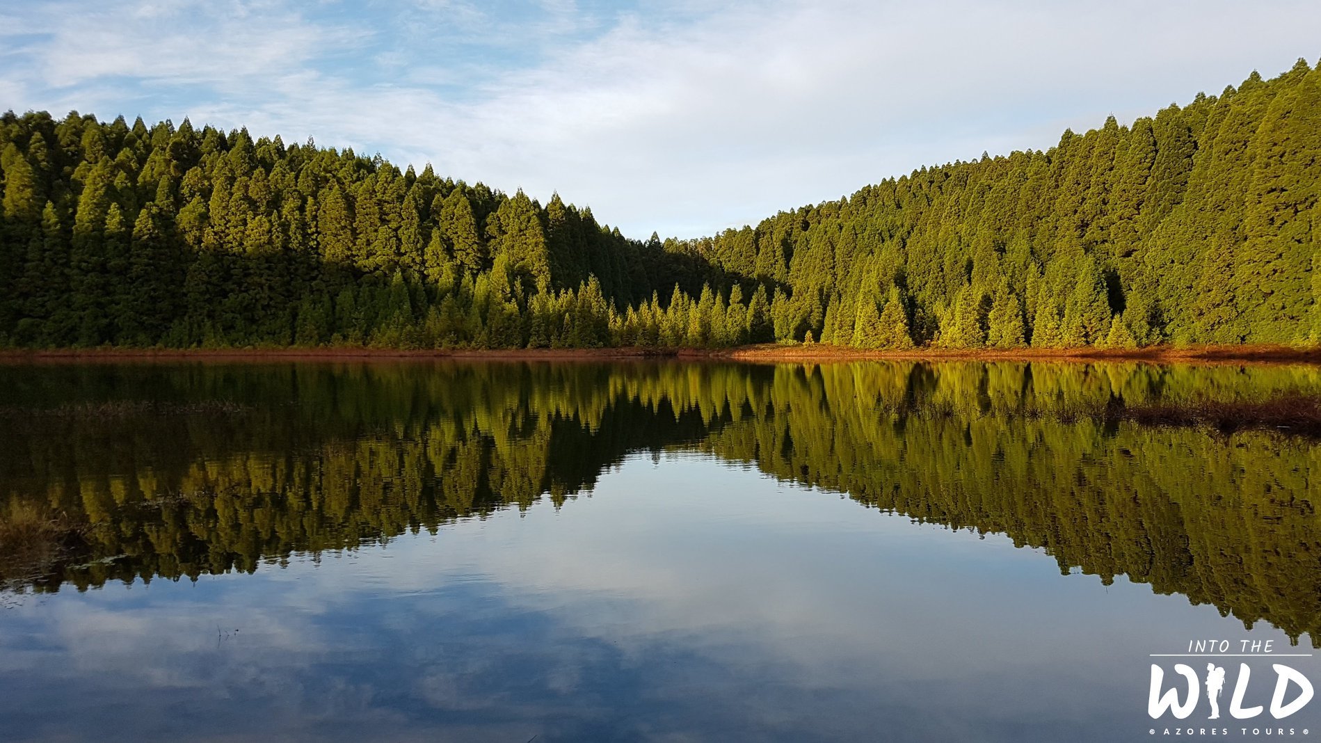 Calm crater lake reflecting clouds along the guided Sete Cidades route