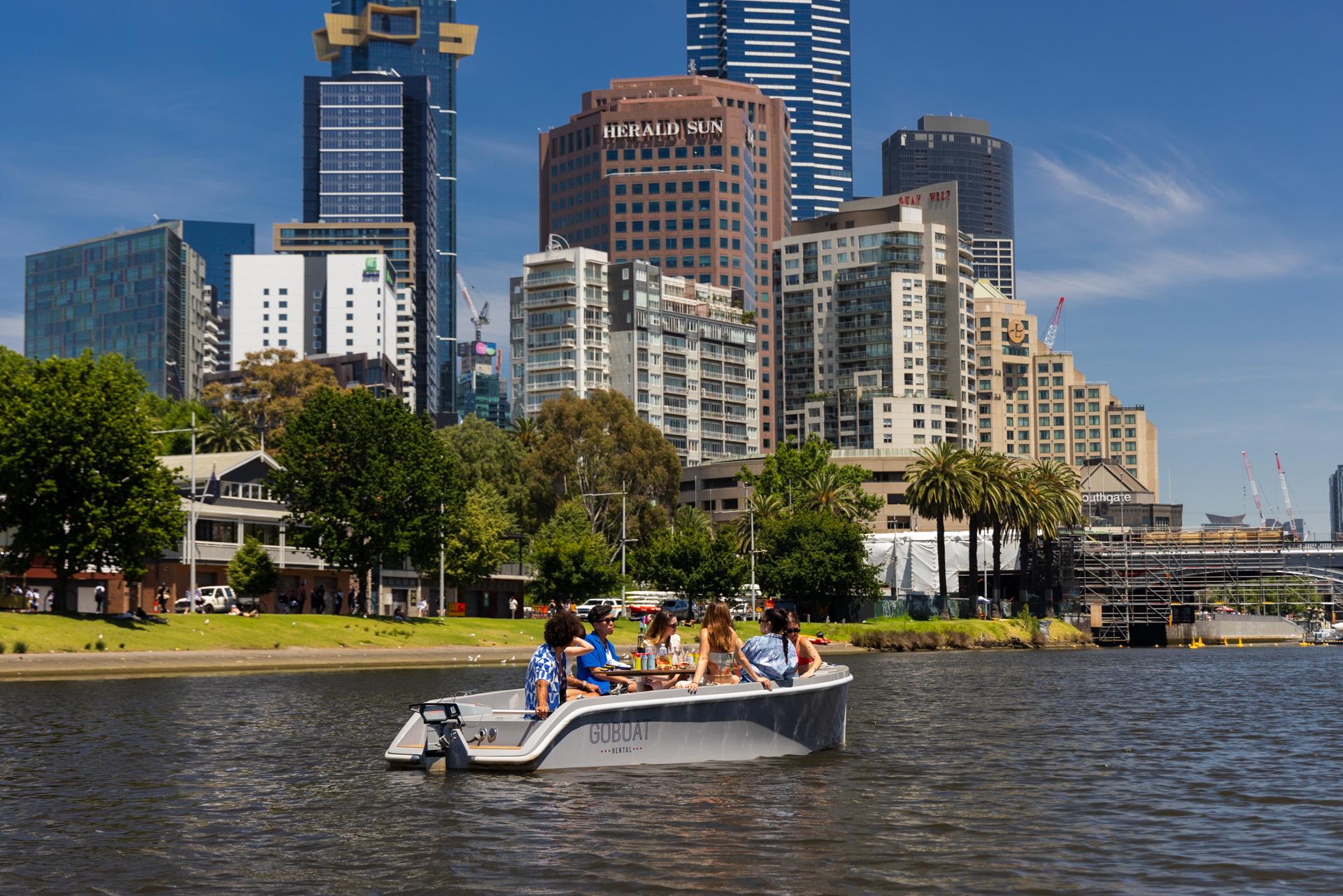 A GoBoat on the Yarra in front of riverside apartment towers