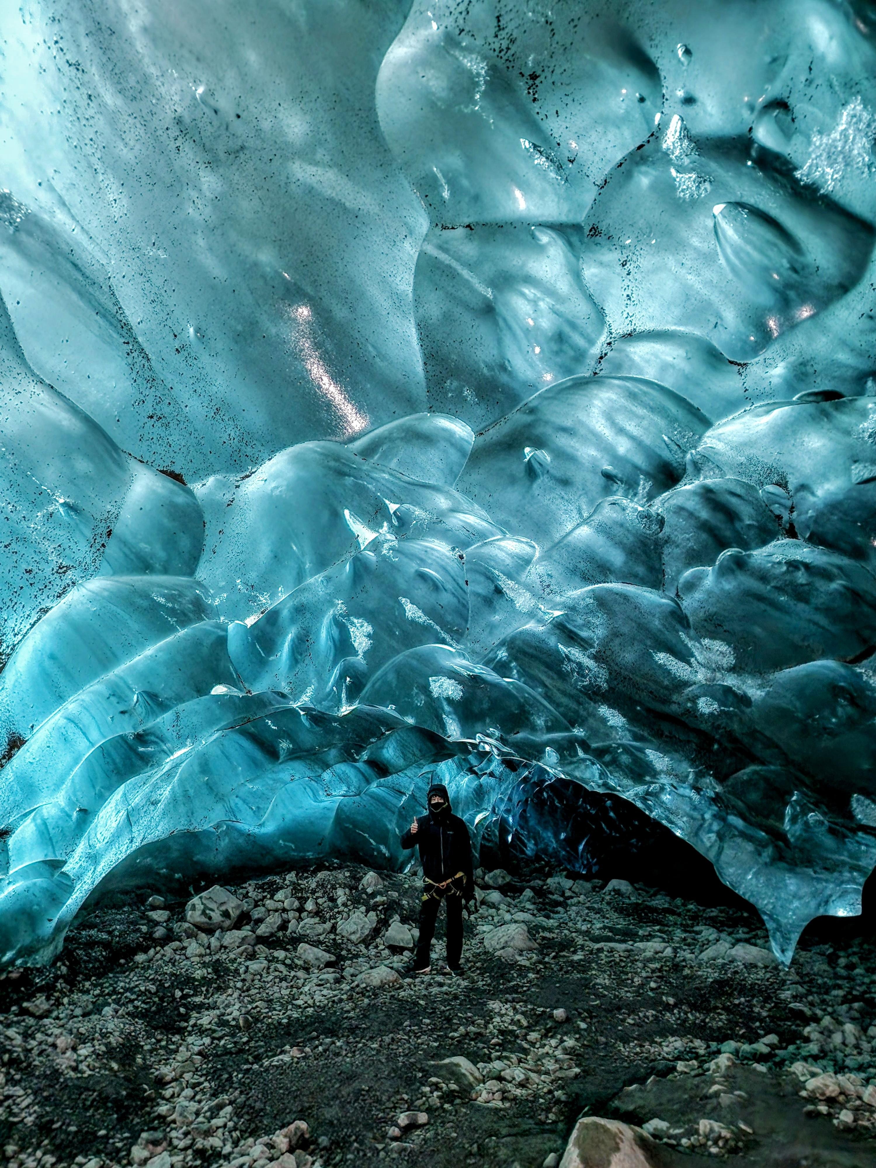 A guided group walking across the ice toward the cave mouth