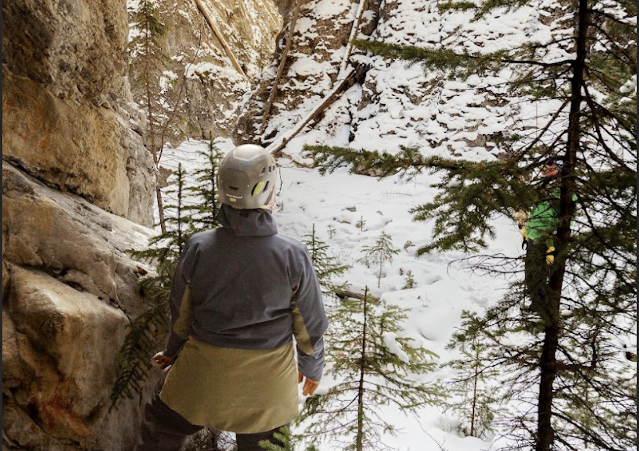Walker in a helmet between the snowy rock walls of Pleckaitis Canyon, Jasper