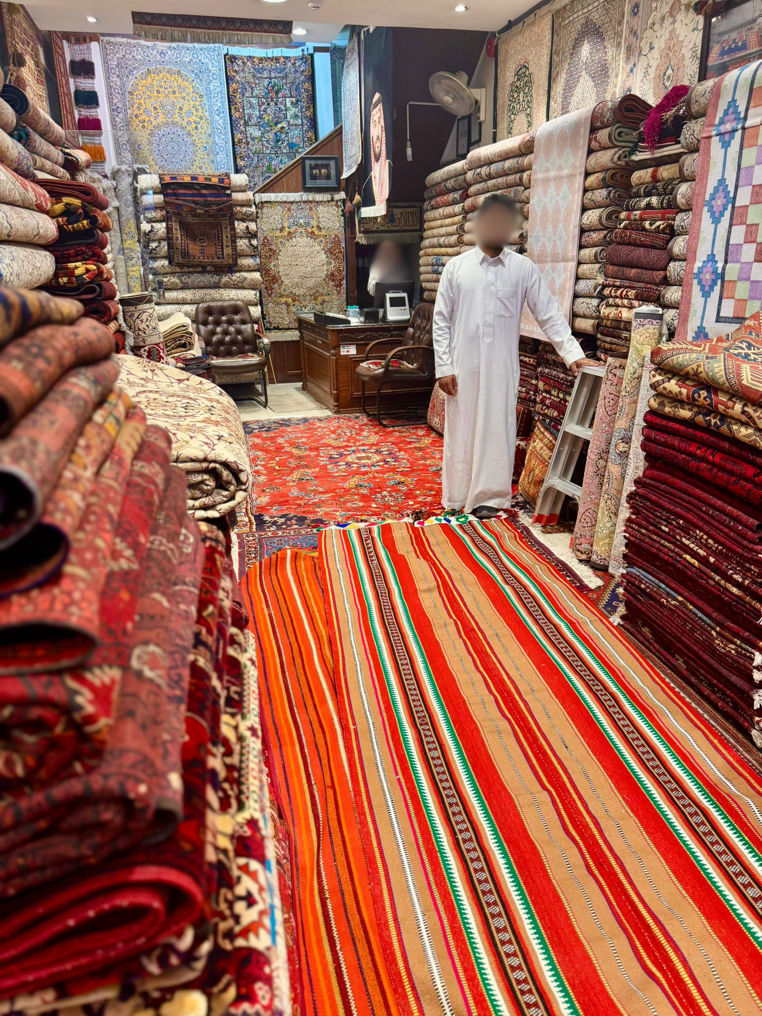 A shopkeeper in his carpet shop among rolls of fabric and rugs in the old city of Riyadh