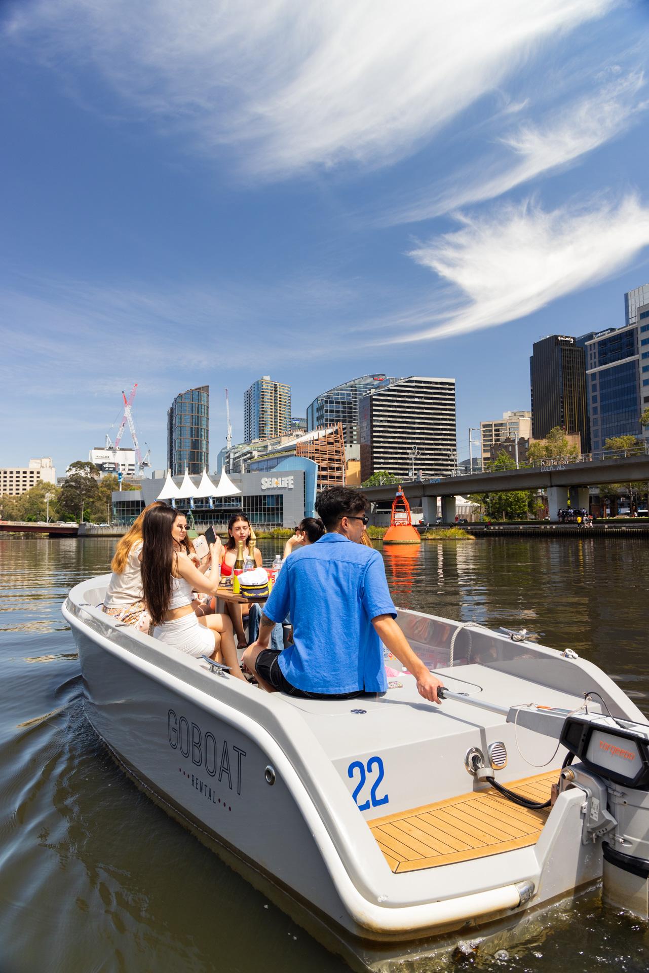 A GoBoat skipper steering past riverside towers