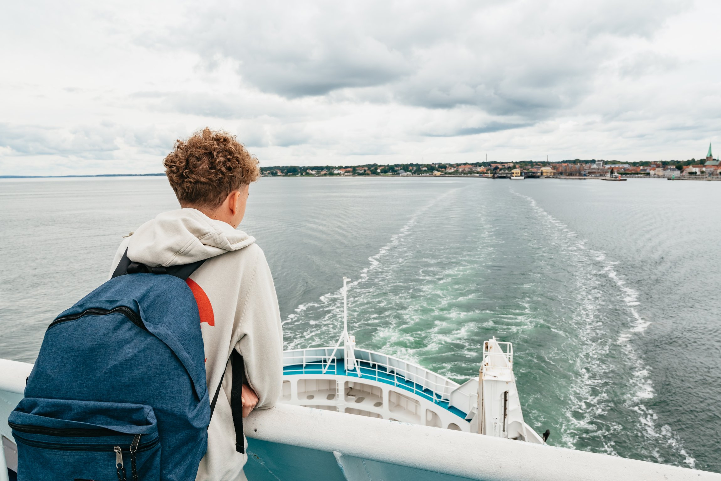 A traveller at the ferry's stern watching the wake across the Øresund