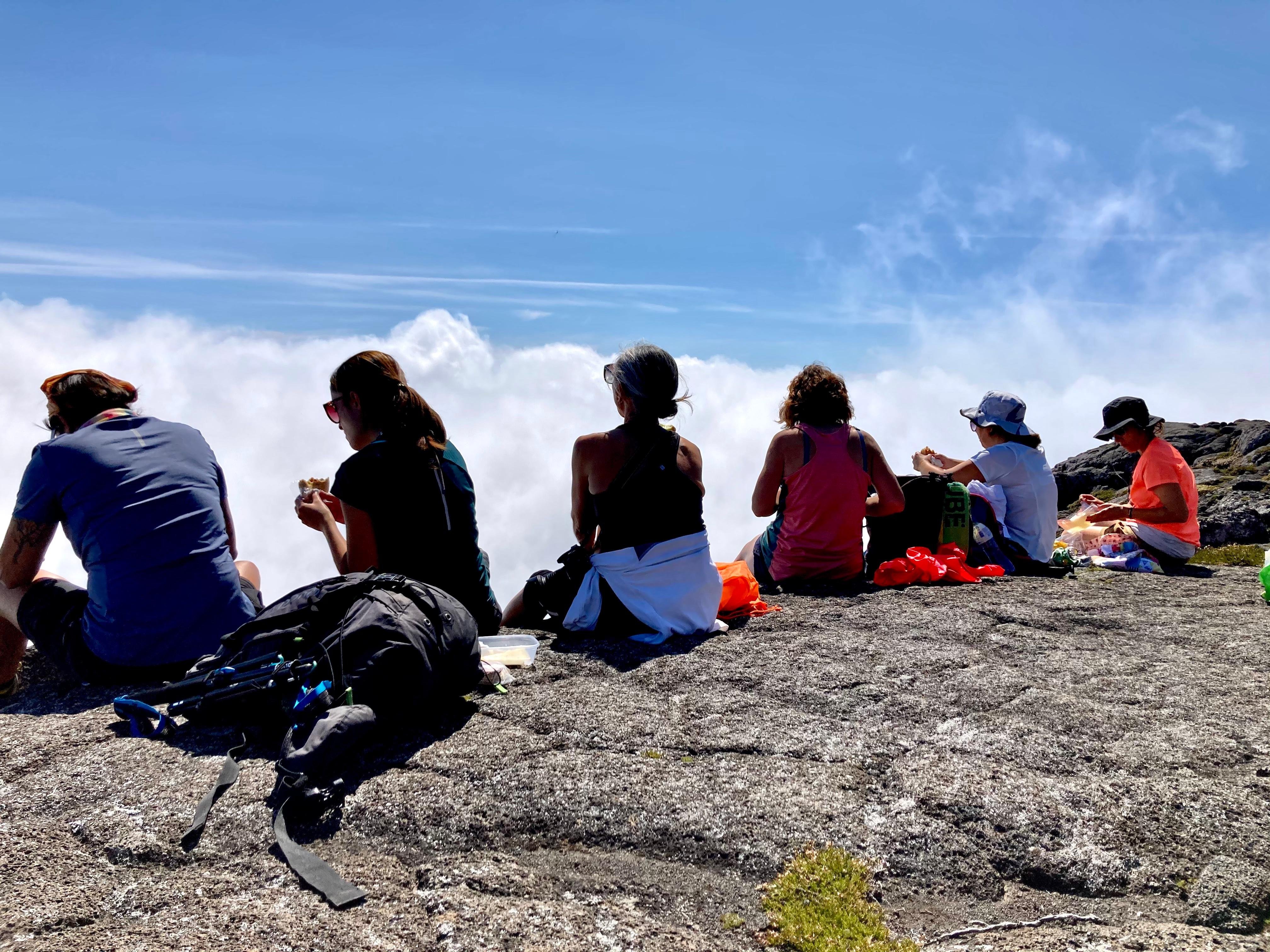Climbers resting on bare rock above the clouds on Pico