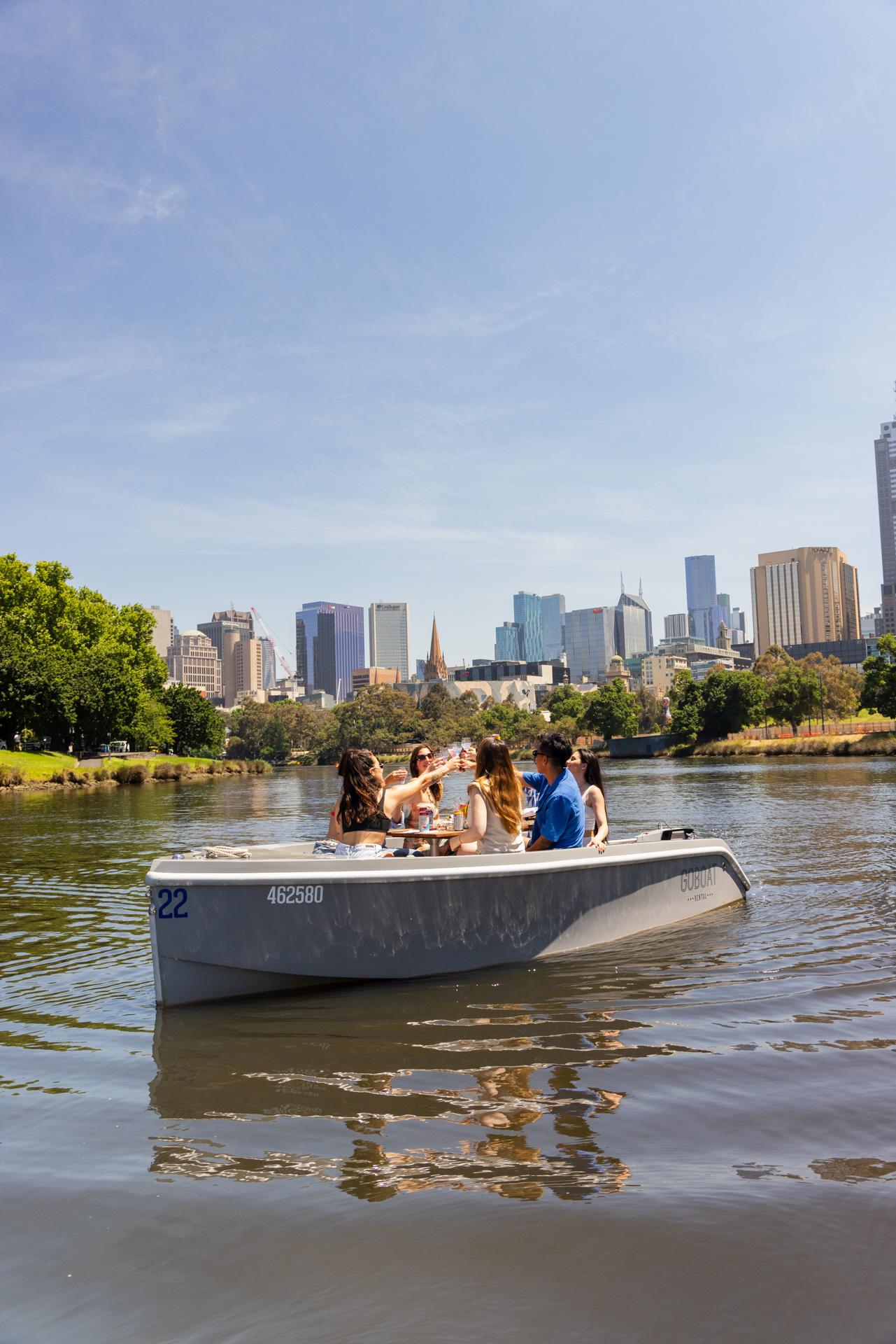 A GoBoat on a calm stretch of the Yarra, the skyline in the distance
