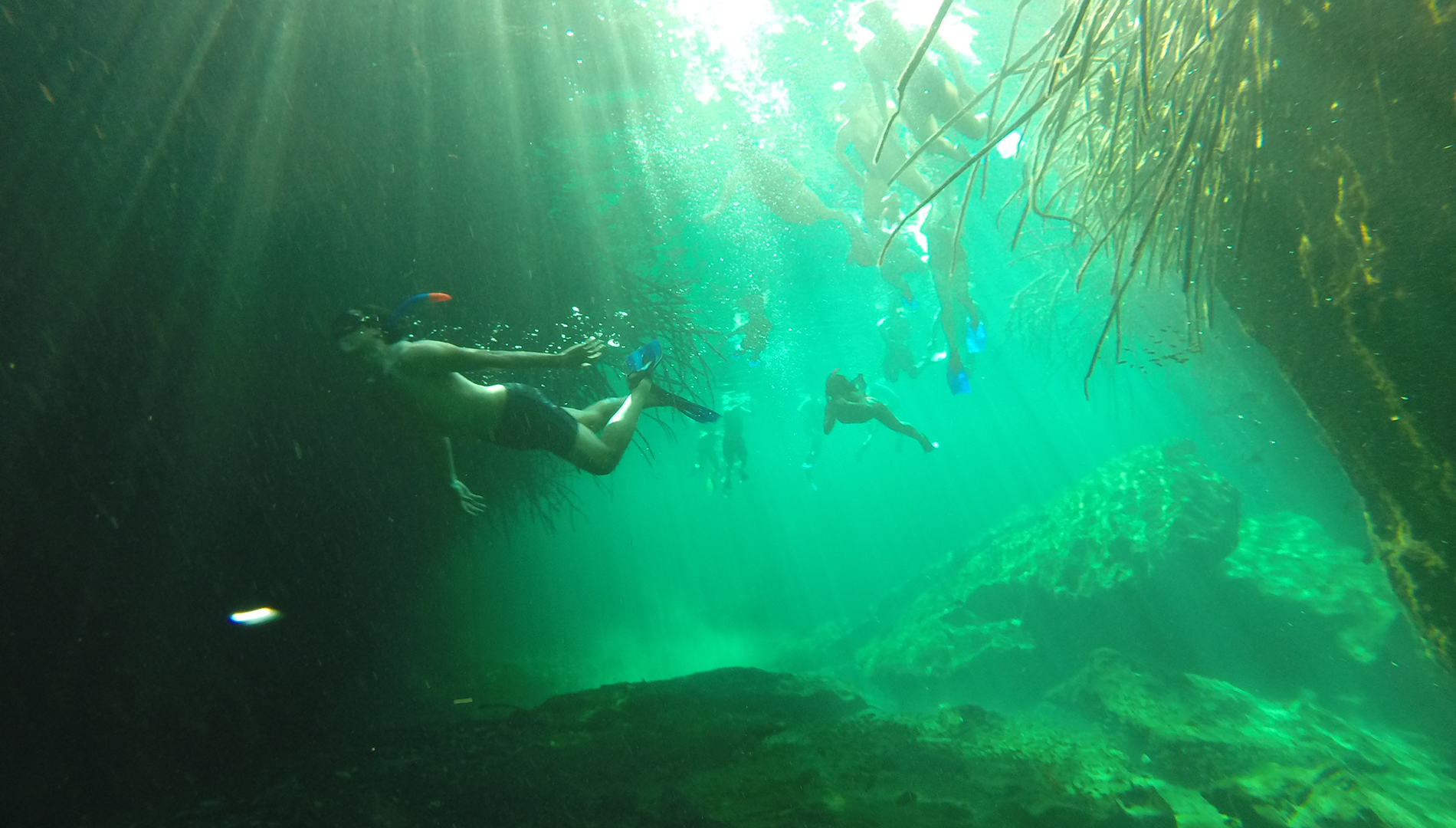 Snorkelers beneath shafts of light in turquoise water