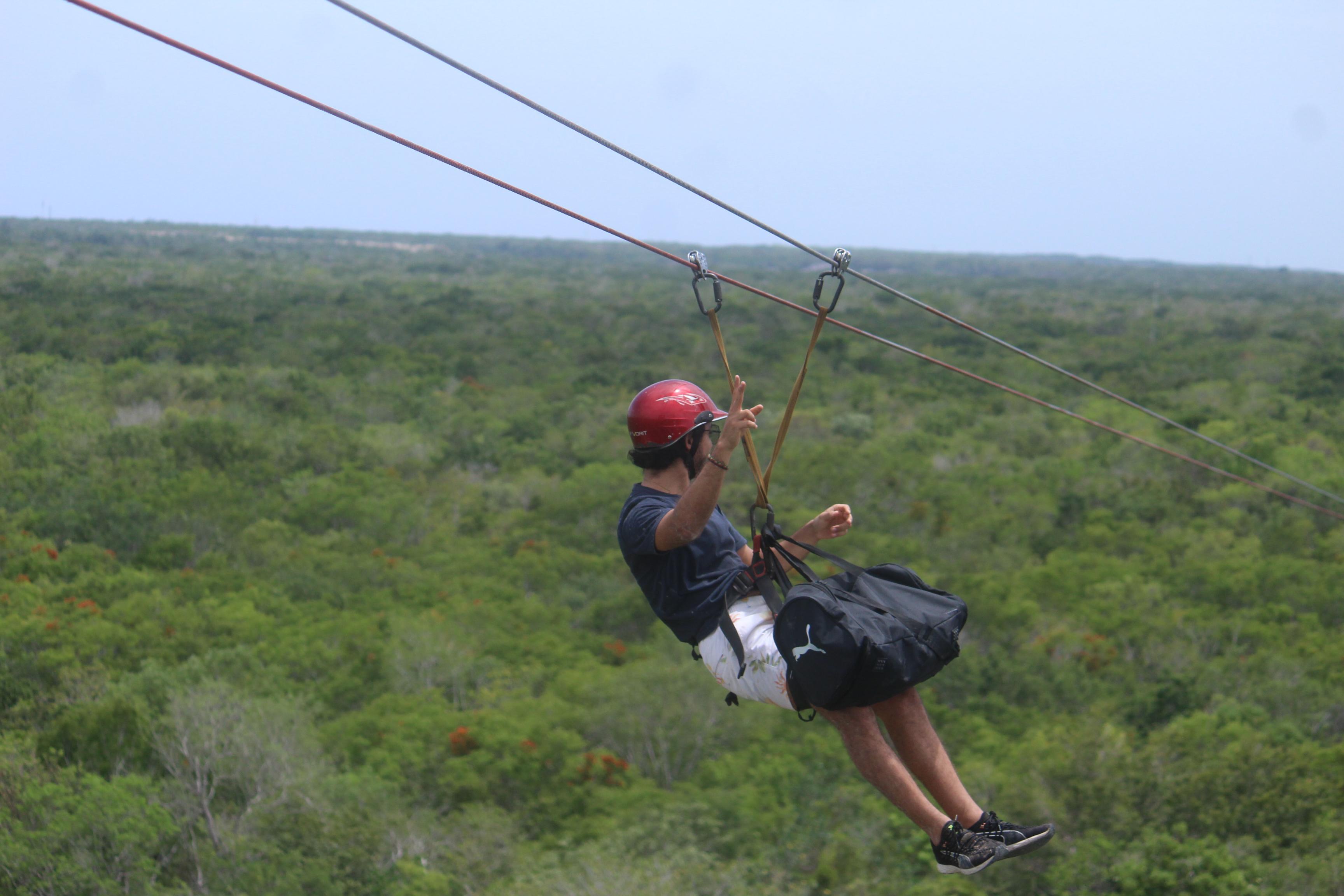 Visitor ziplining over green jungle canopy