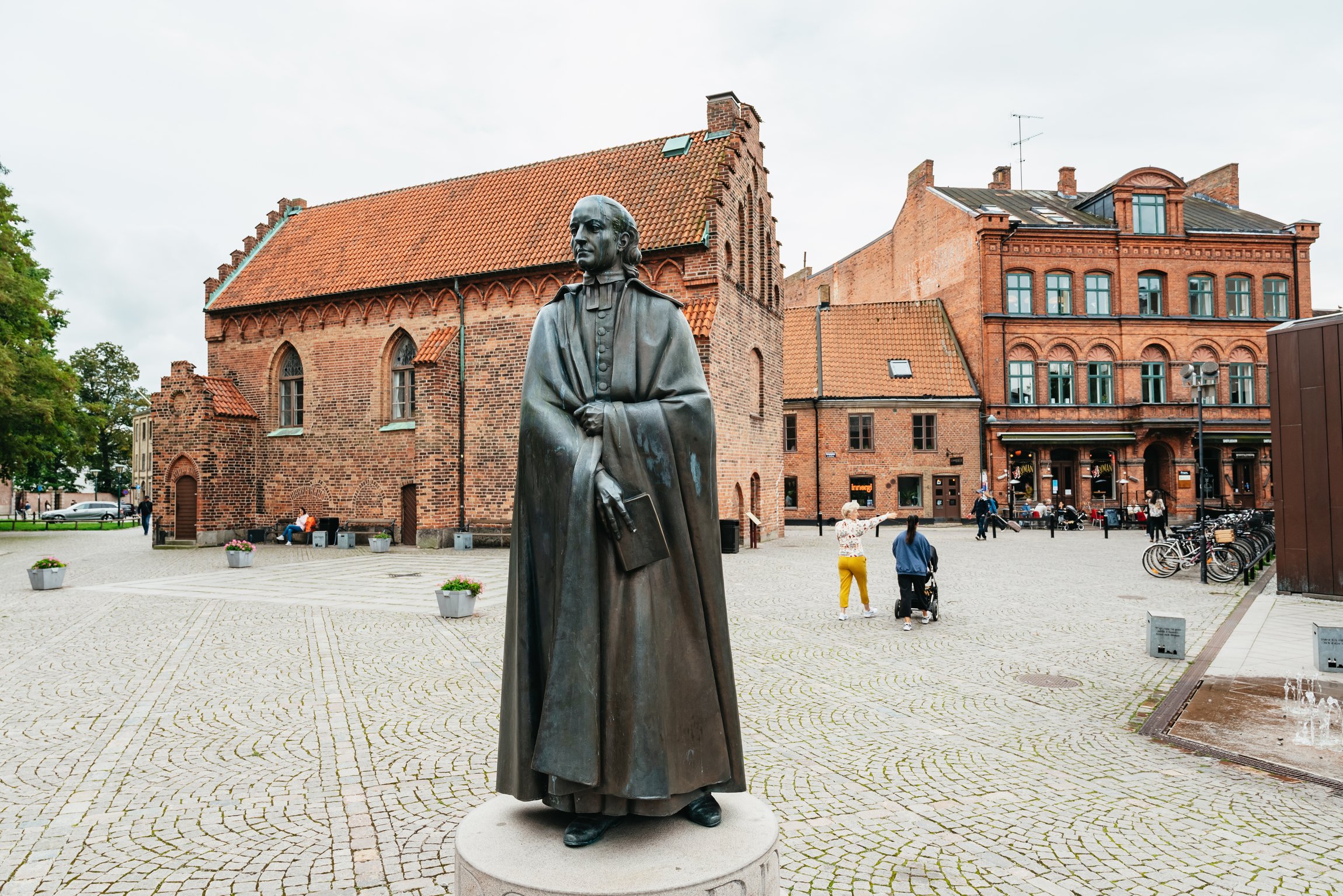 A bronze statue on a cobbled square in Lund, red-brick buildings behind