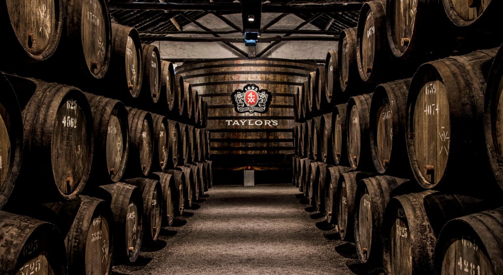 Lang kælder med portvinsfade i række under loftet hos Taylor's i Porto