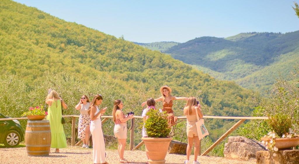 Gæster står på en terrasse med urtepotter og kigger ud over grønne bjerge i Toscana