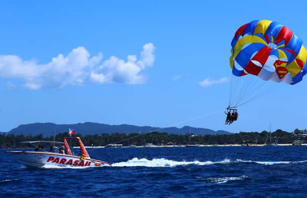 Boracay parasailing over the coastline with a speedboat below