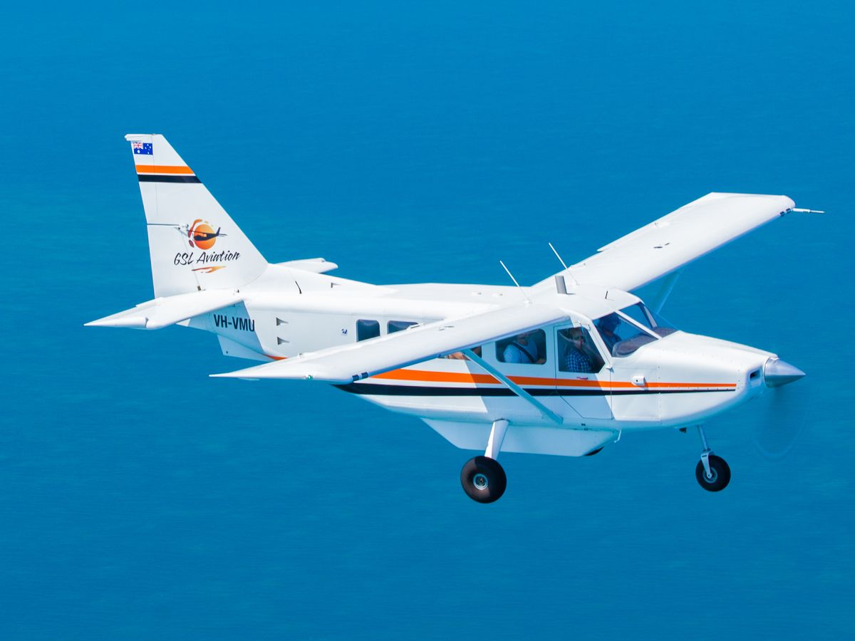 High-wing scenic aircraft flying over the Coral Sea