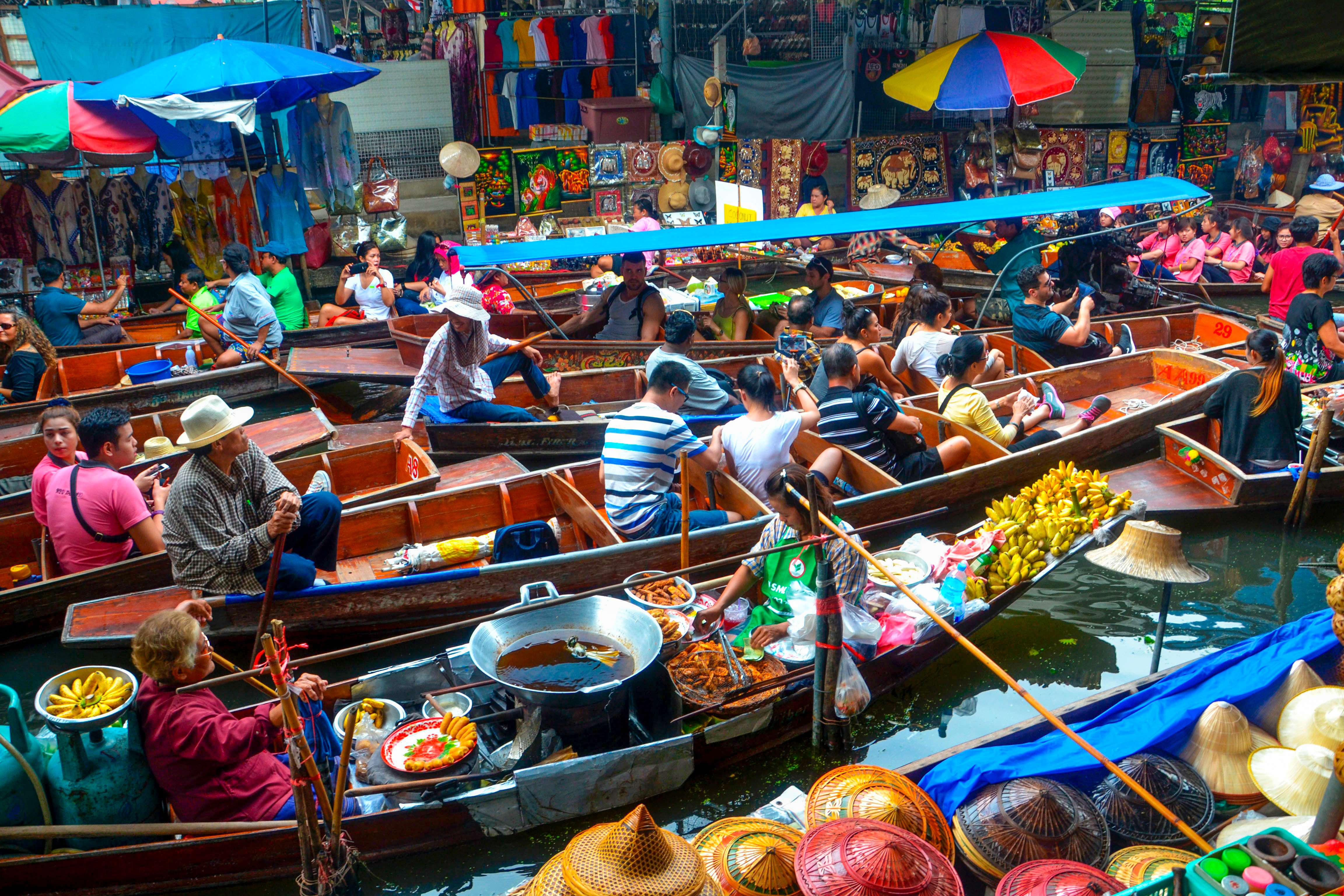 Pasar terapung yang ramai di Bangkok dengan pedagang di atas perahu yang menjual barang.