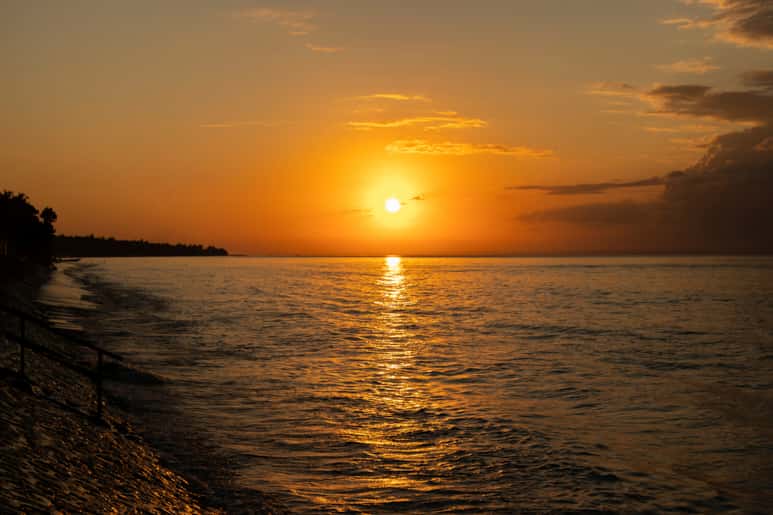 A beautiful sunset over the ocean with a golden sky and calm waters.