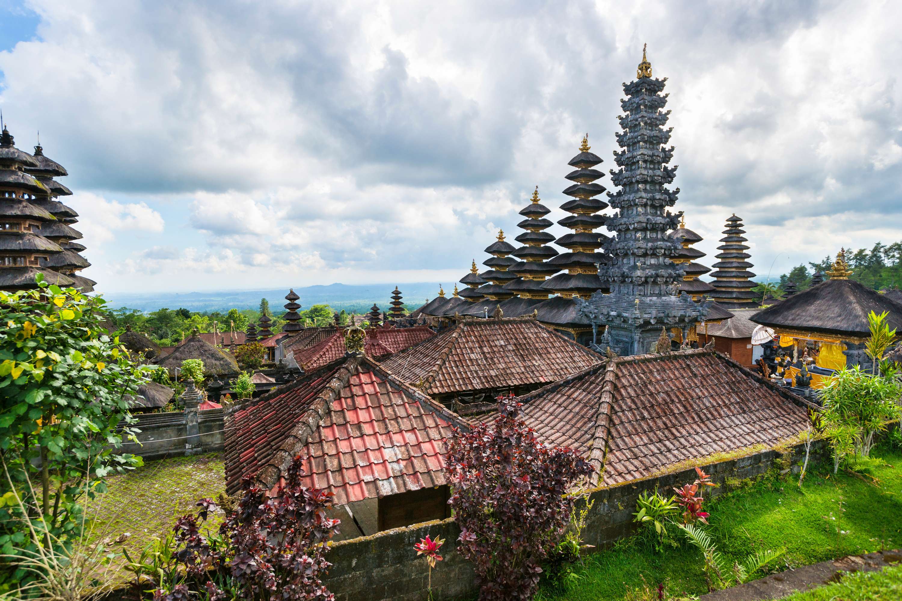 Besakih Great Temple complex with tiered pagodas and a tall stone tower in the hills.