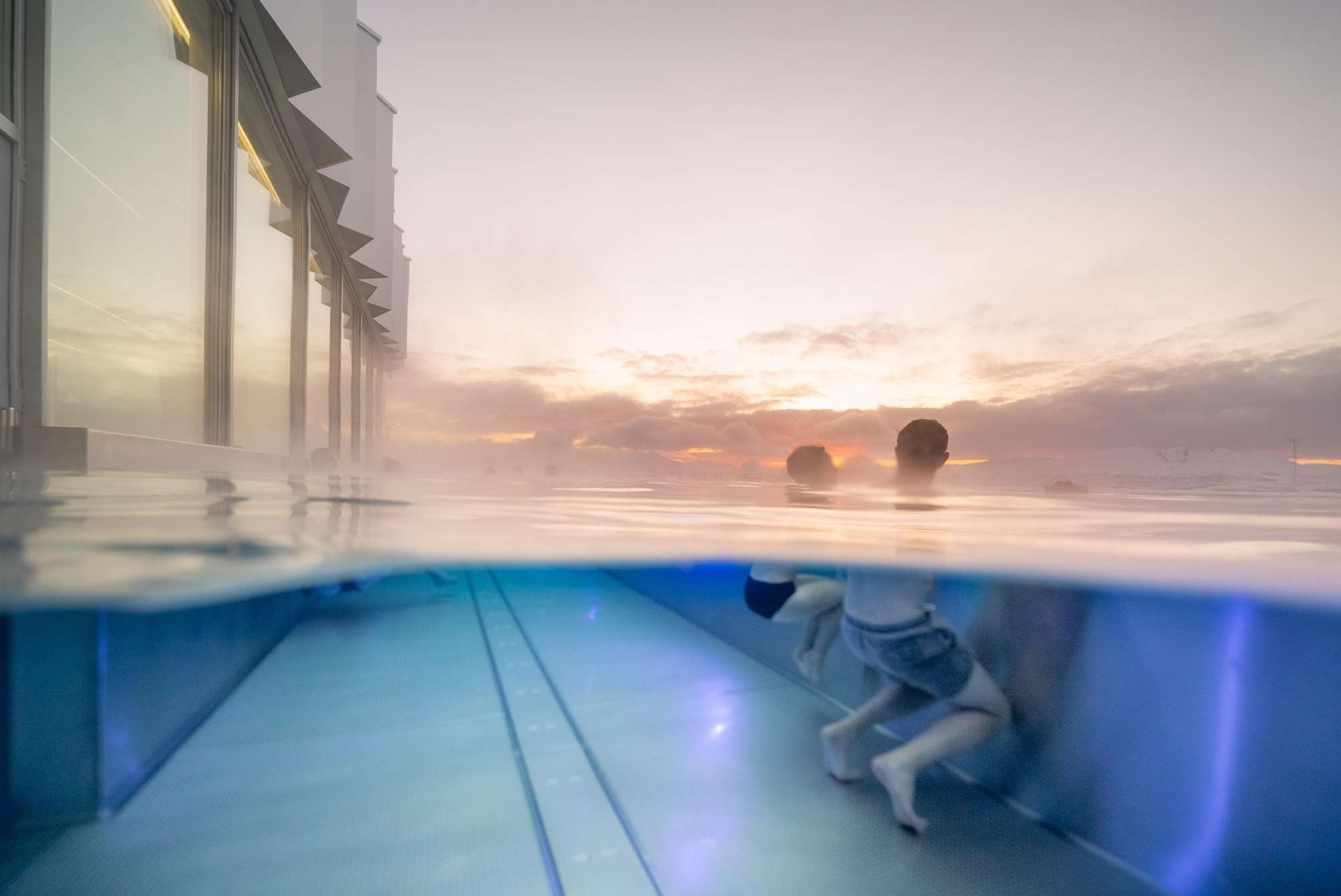 Piscina exterior climatizada del Tromsøbadet en Tromsø: agua humeante frente a las montañas nevadas del Ártico, con sauna finlandesa, hammam y piscina olímpica de 50 metros en el interior