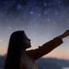 Woman pointing at stars at dusk