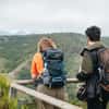 Two hikers at viewpoint over green hills