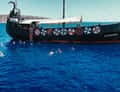 Dark wooden ship with swimmers in water