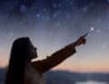 Woman pointing at stars at dusk