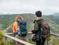 Two hikers at viewpoint over green hills