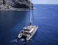 Catamaran under dark cliff