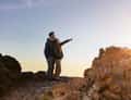 Man pointing at sunset on rocks