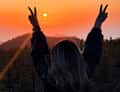 Woman with raised arms at sunset
