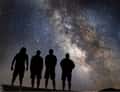 Four silhouettes under Milky Way