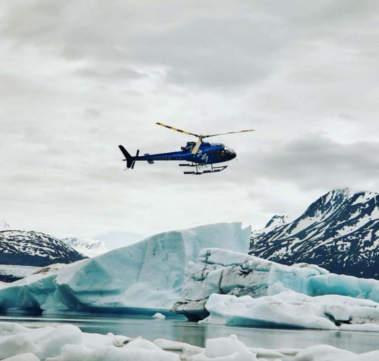 Helicopter landed beside icebergs at Bear Glacier Lagoon near Seward, Alaska