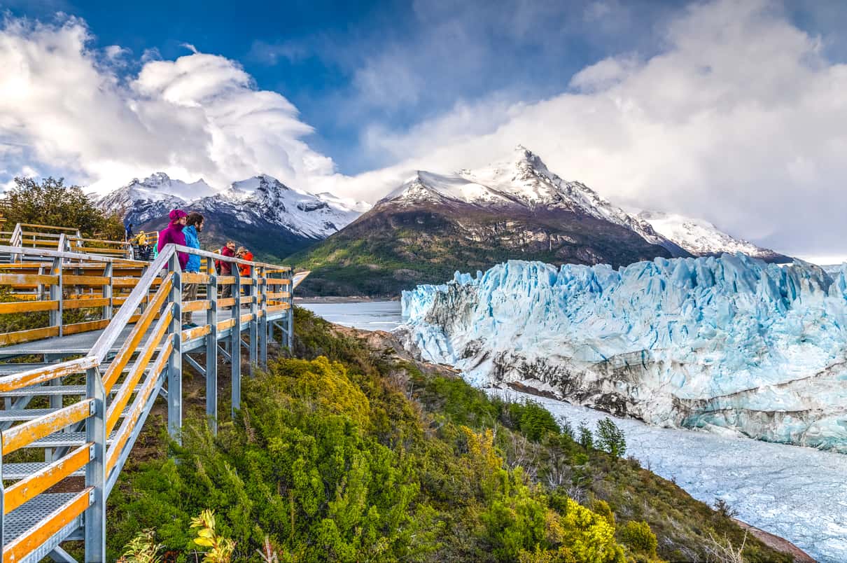 Trekkers in crampons walking across the blue ice of Perito Moreno Glacier