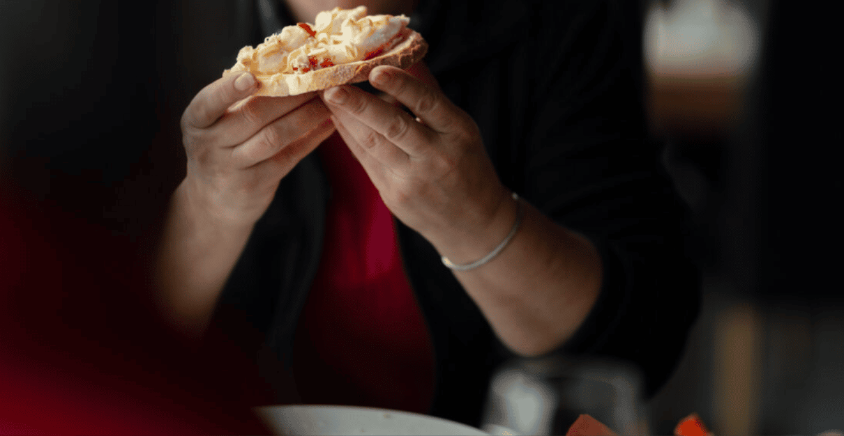 A safari guest holding a slice of white bread topped with king crab meat and mayonnaise