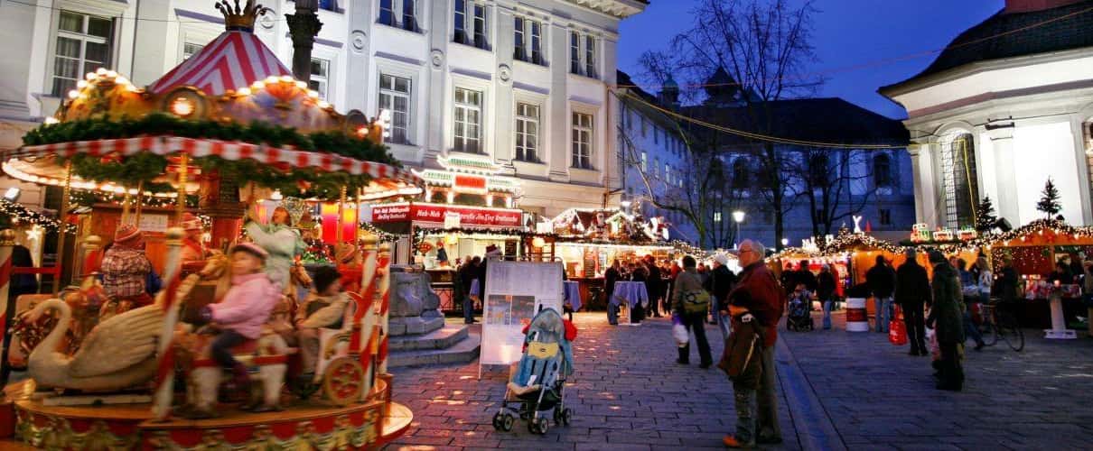 Wooden Christmas huts and strolling visitors on a square in Zurich's Old Town at dusk