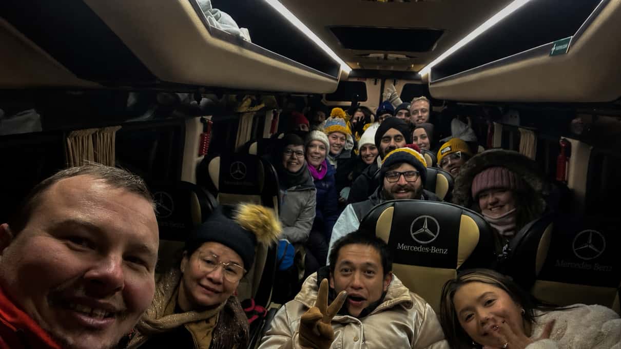 A smiling small group taking a selfie inside a minibus before a Reykjavík aurora hunt