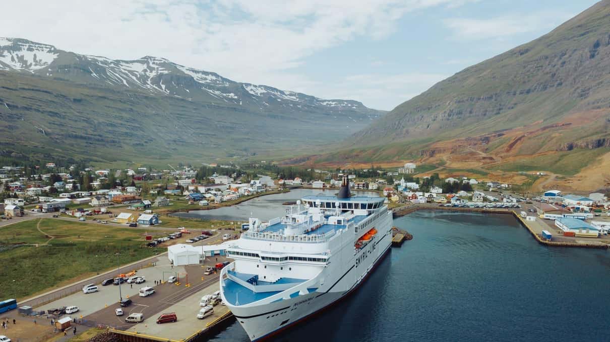 A cruise ship docked at Seyðisfjörður below snow-streaked mountains at the head of the fjord