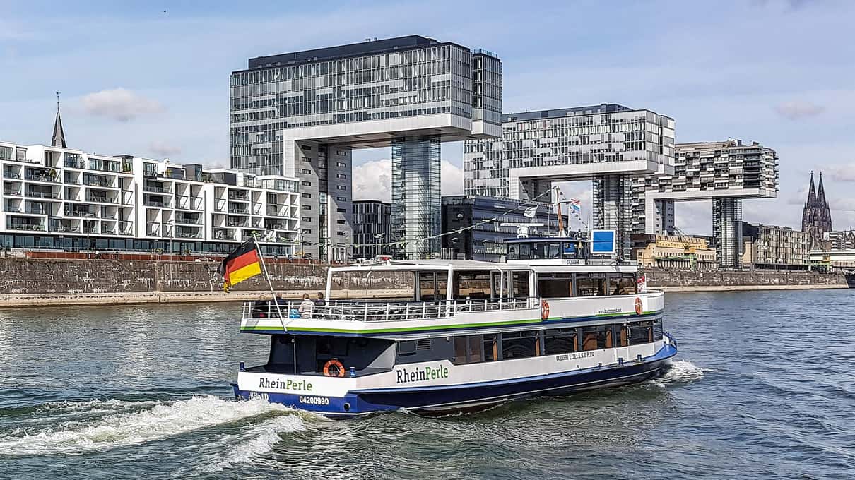 White KölnTourist sightseeing boat passing the Rheinauhafen crane houses on the Rhine in Cologne